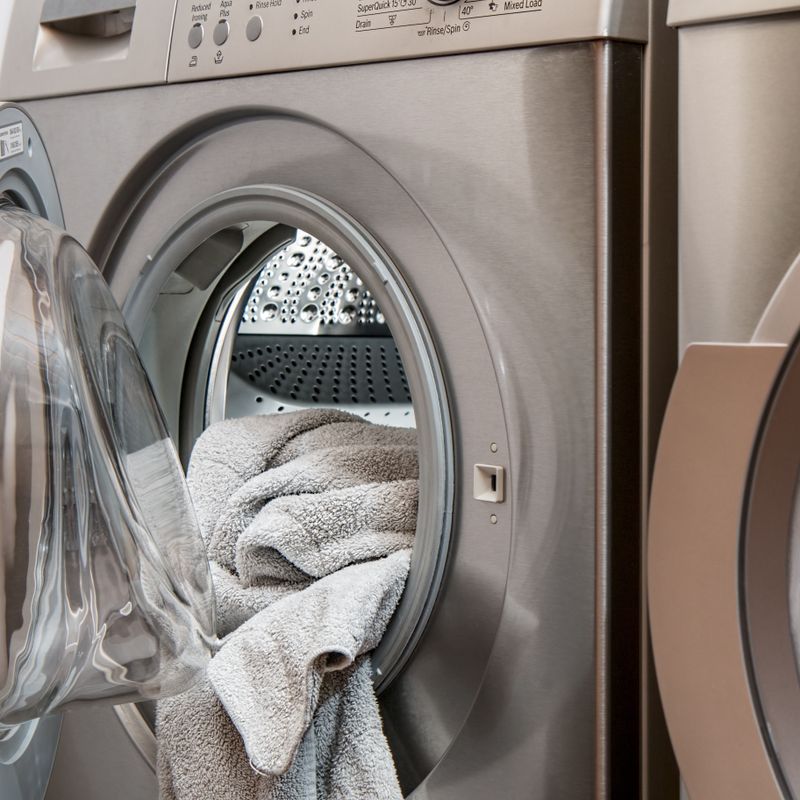 An open washing machine with towels hanging out. Image for About Rochelle Cleaners.